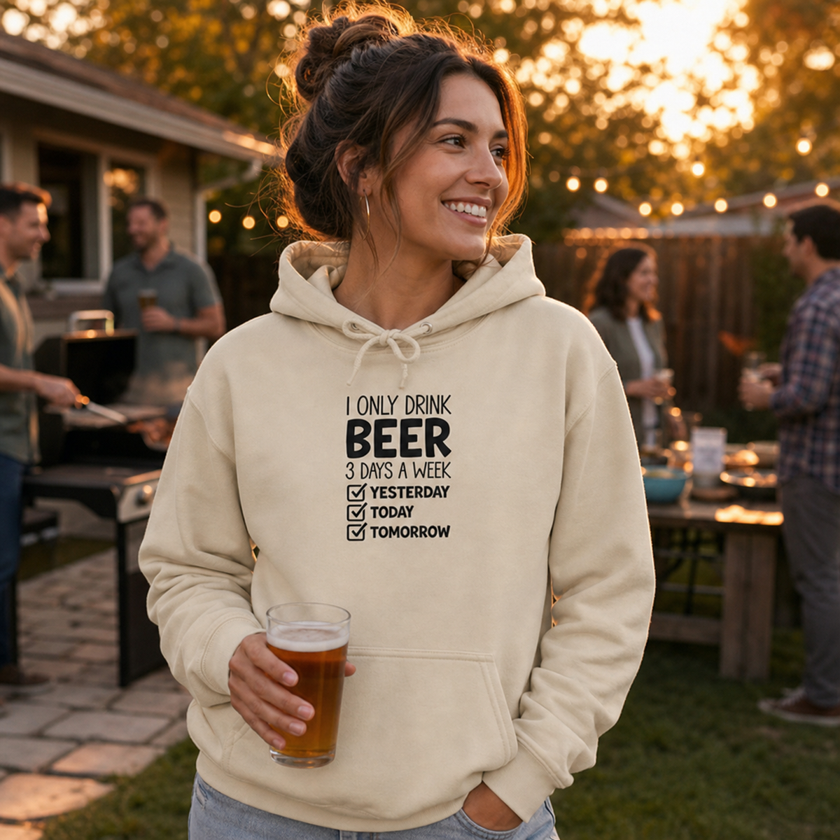 Young woman wearing I Only Drink Beer 3 Days a Week hoodie at a backyard barbecue