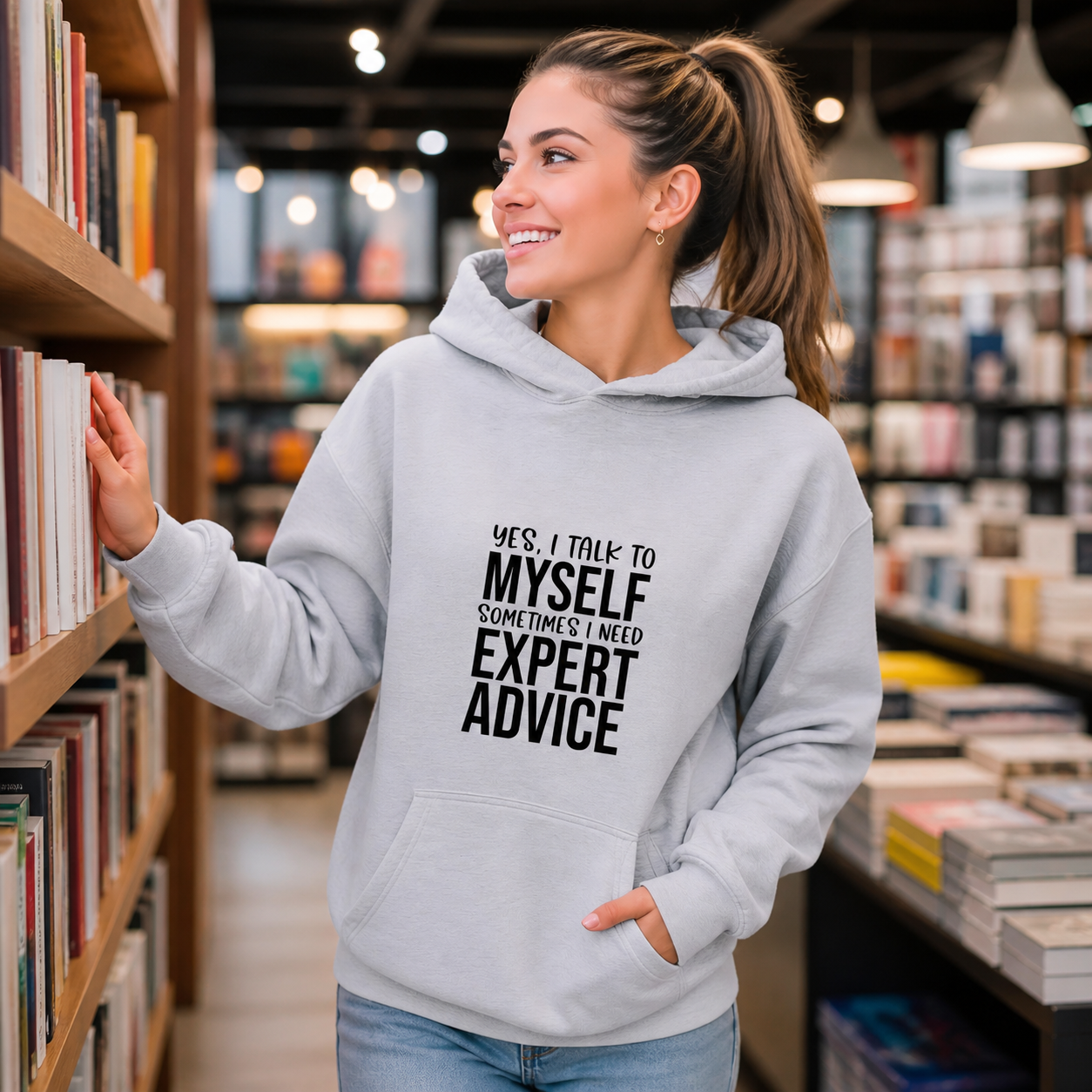 Young woman wearing Yes I Talk to Myself expert advice hoodie in a bookstore