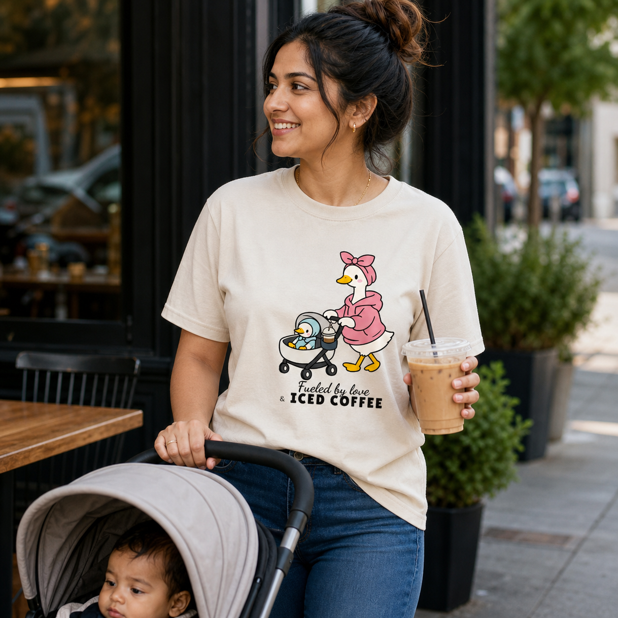 South Asian mom wearing Fueled by Love and Iced Coffee graphic T-shirt with stroller