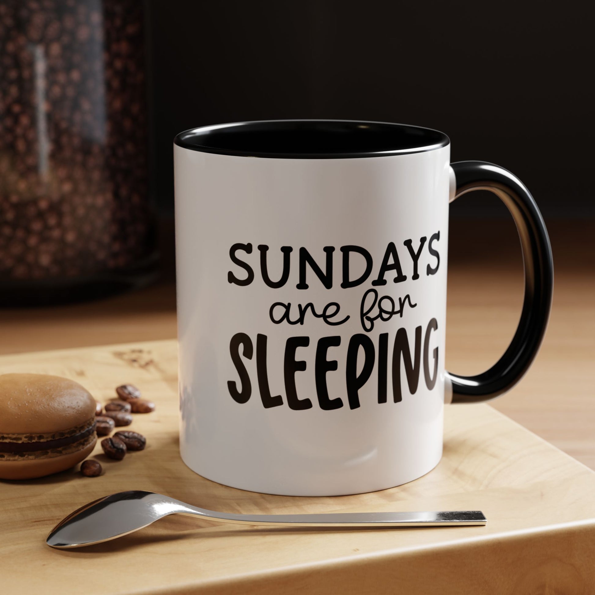 funny coffee mug gift with 'Sundays Are For Sleeping' design, black handle, beside a spoon and macarons