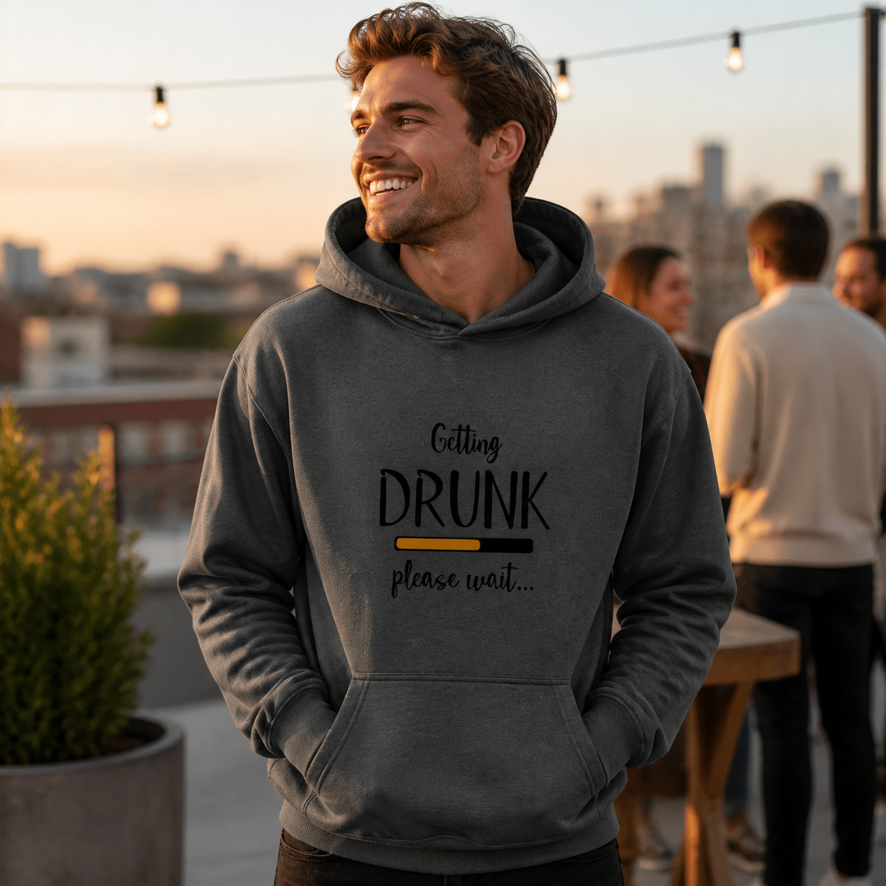Young man wearing Getting Drunk Please Wait graphic hoodie at a rooftop gathering