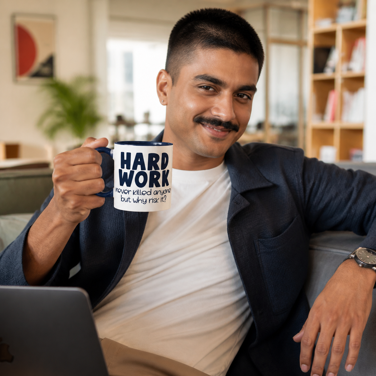 Young professional holding navy-accent Hard Work Never Killed Anyone mug in a coworking lounge