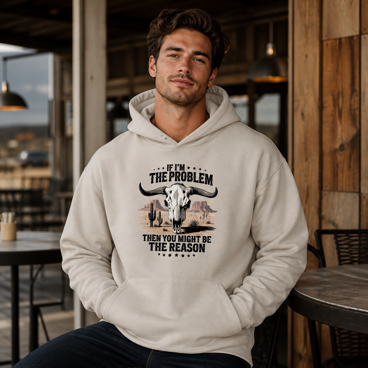 Young man wearing If I'm the Problem bull skull graphic hoodie at a ranch cafe