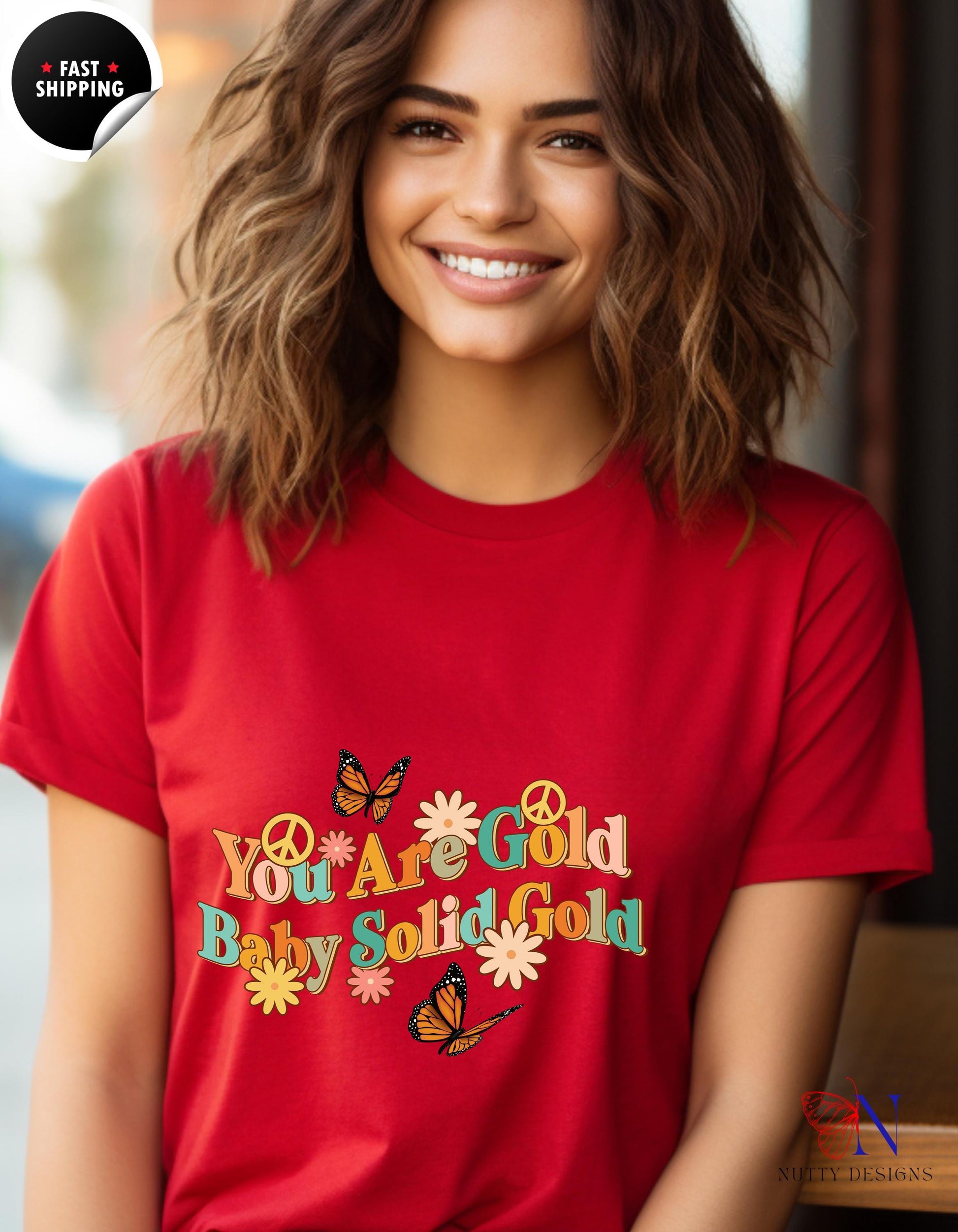 a woman wearing a red t - shirt that says you are gold, baby gold