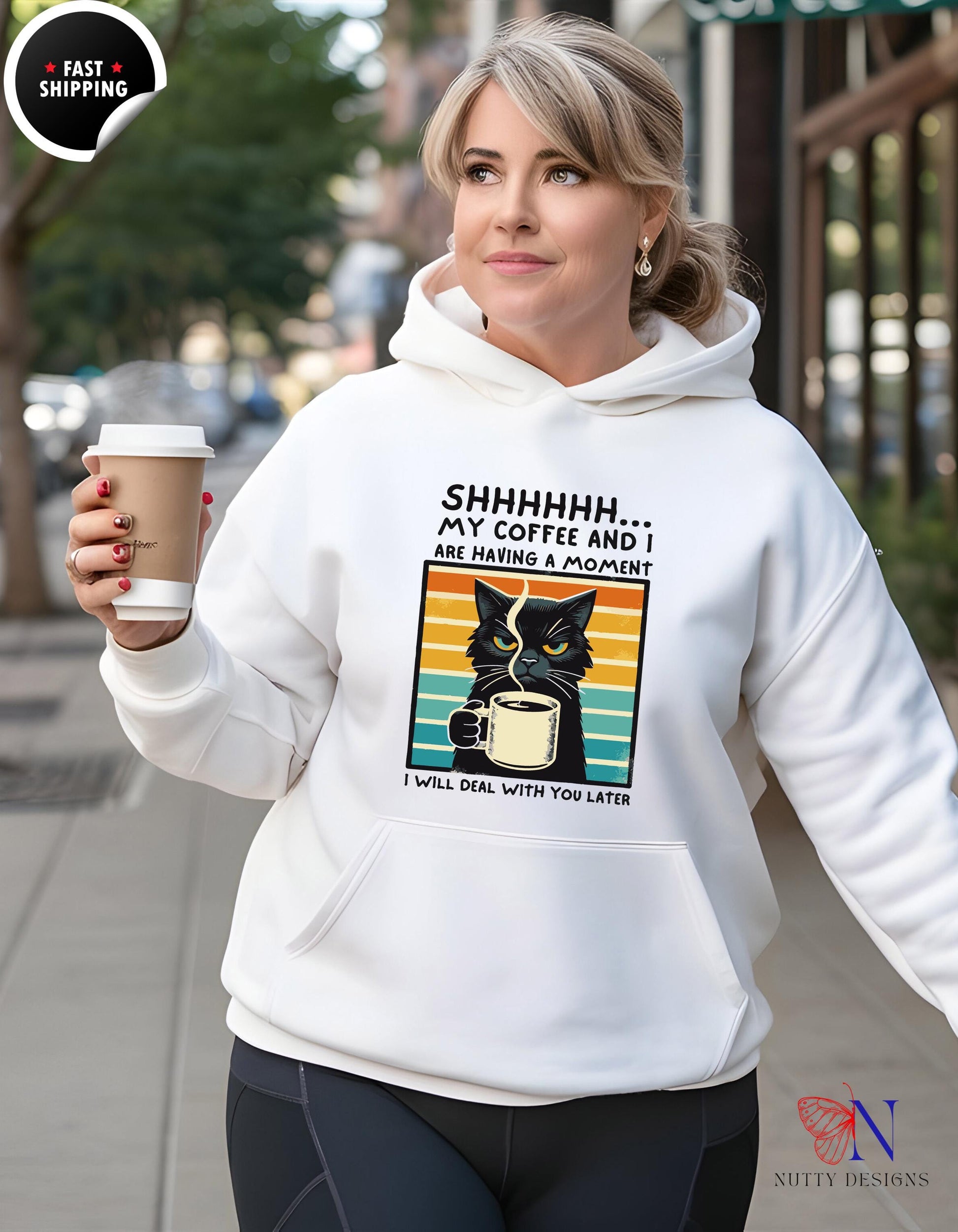 Woman wearing a funny unisex hoodie saying 'SHHHHHH... My Coffee and I are having a moment' with a coffee cup.