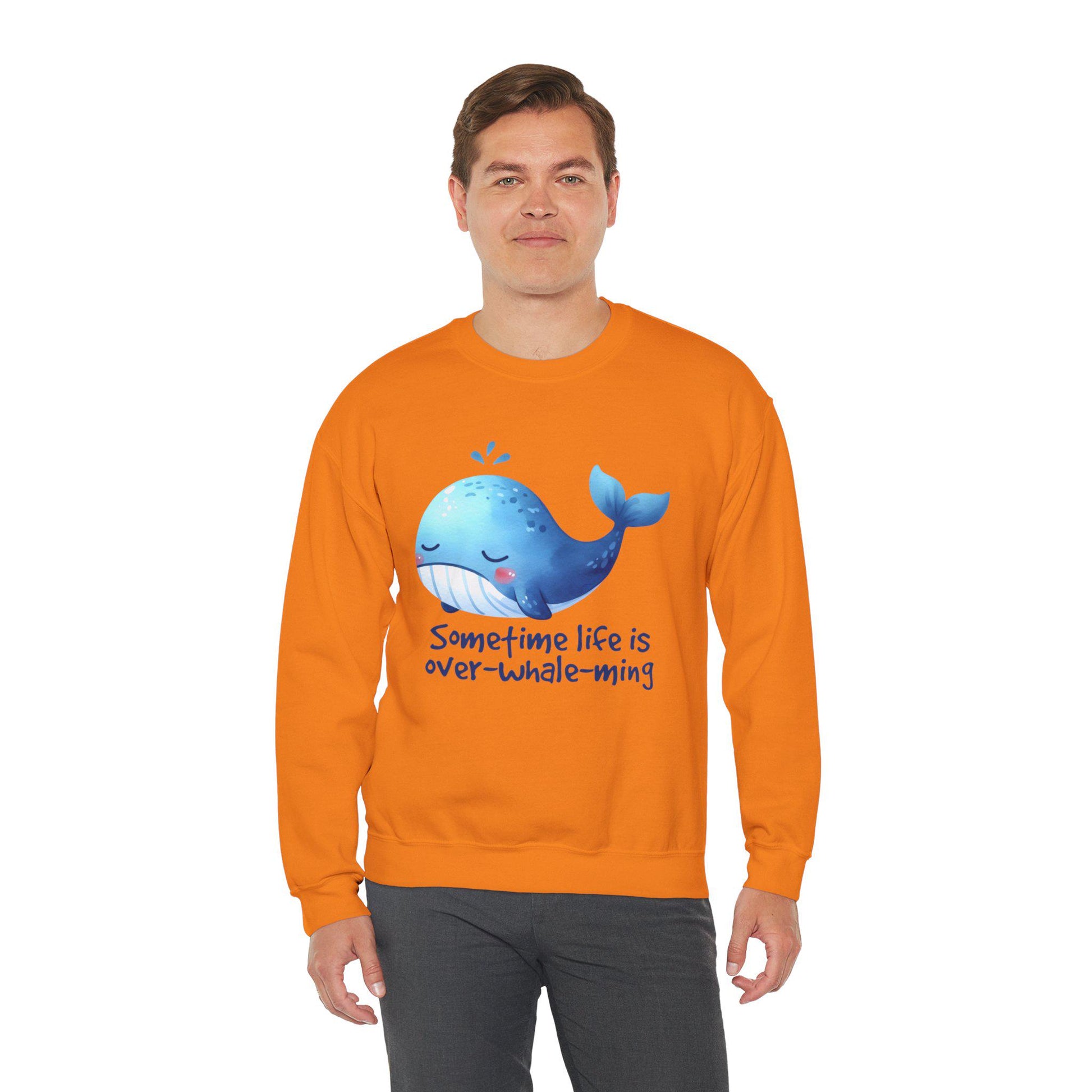 Bright orange sweatshirt featuring a cheerful whale and the phrase 'Sometime life is over-whale-ming'.