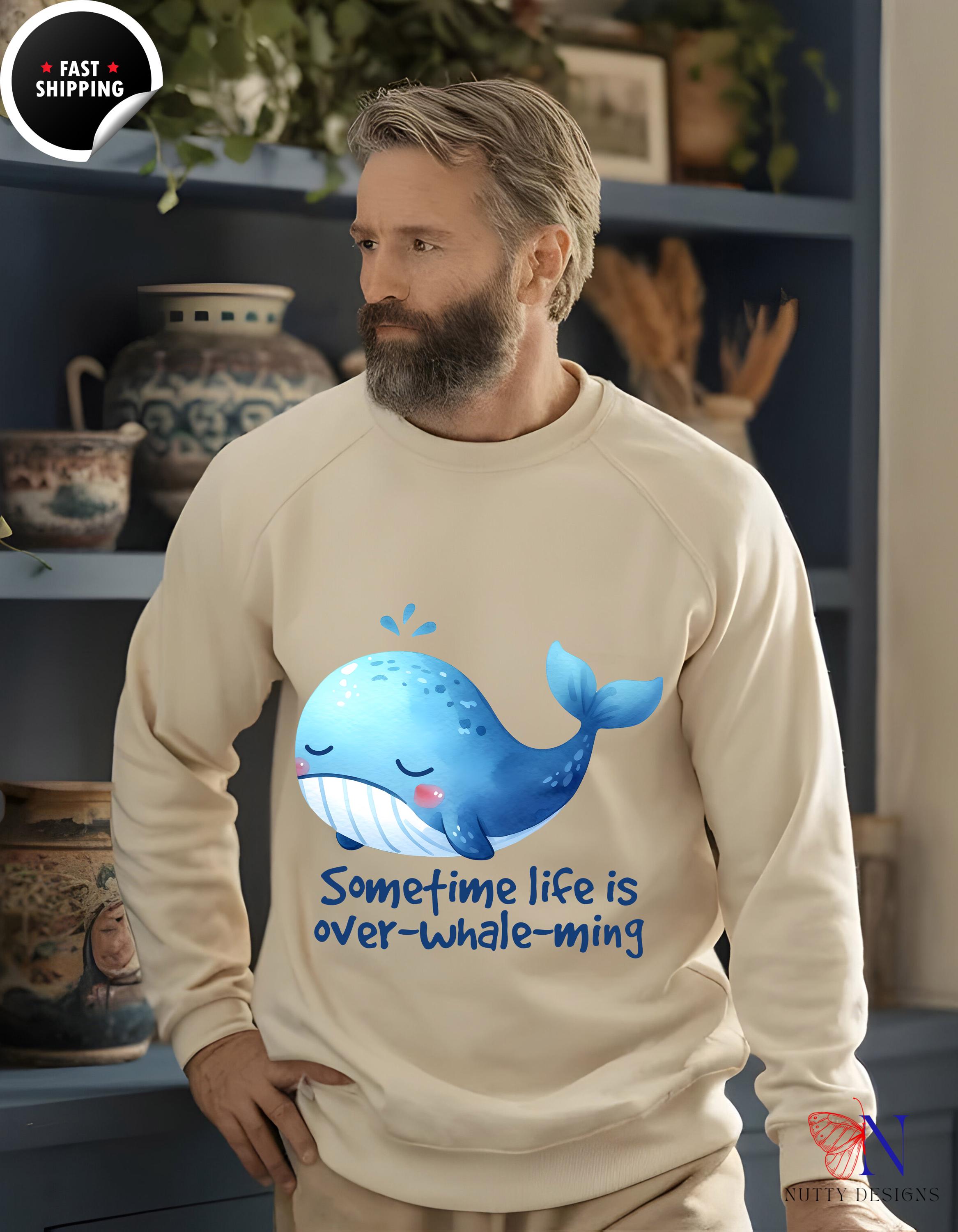 Man wearing a cream sweatshirt with 'Sometime life is over-whale-ming' and a cute whale graphic.