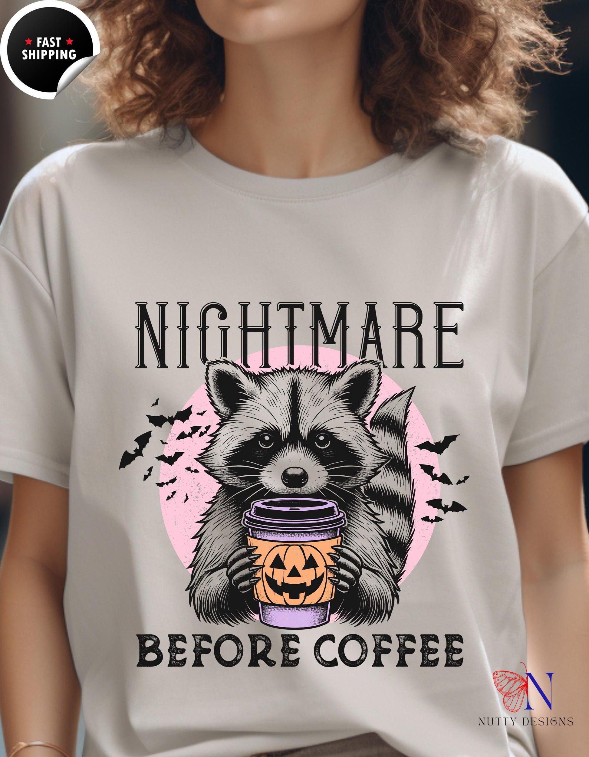 a woman wearing a t - shirt with a raccoon holding a cup of