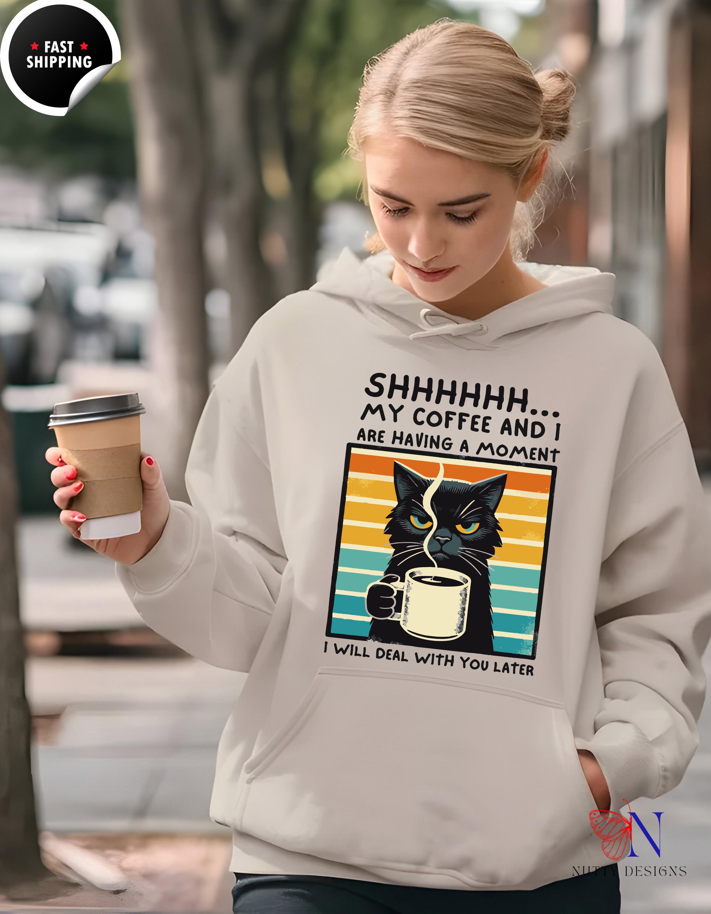 Funny unisex hoodie with cat graphic saying 'Shhhhh... My Coffee and I are having a moment', perfect for cozy days.