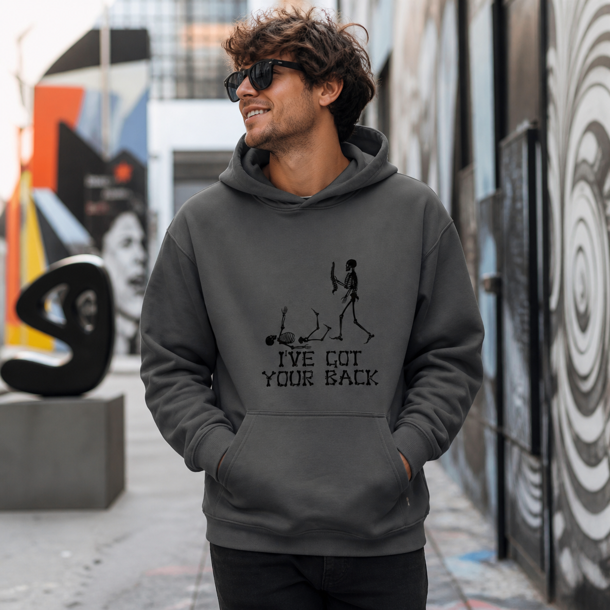 Young man wearing I've Got Your Back skeleton graphic hoodie in an art district