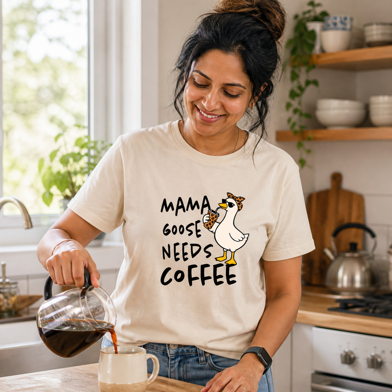 South Asian mom wearing Mama Goose Needs Coffee graphic T-shirt while pouring coffee