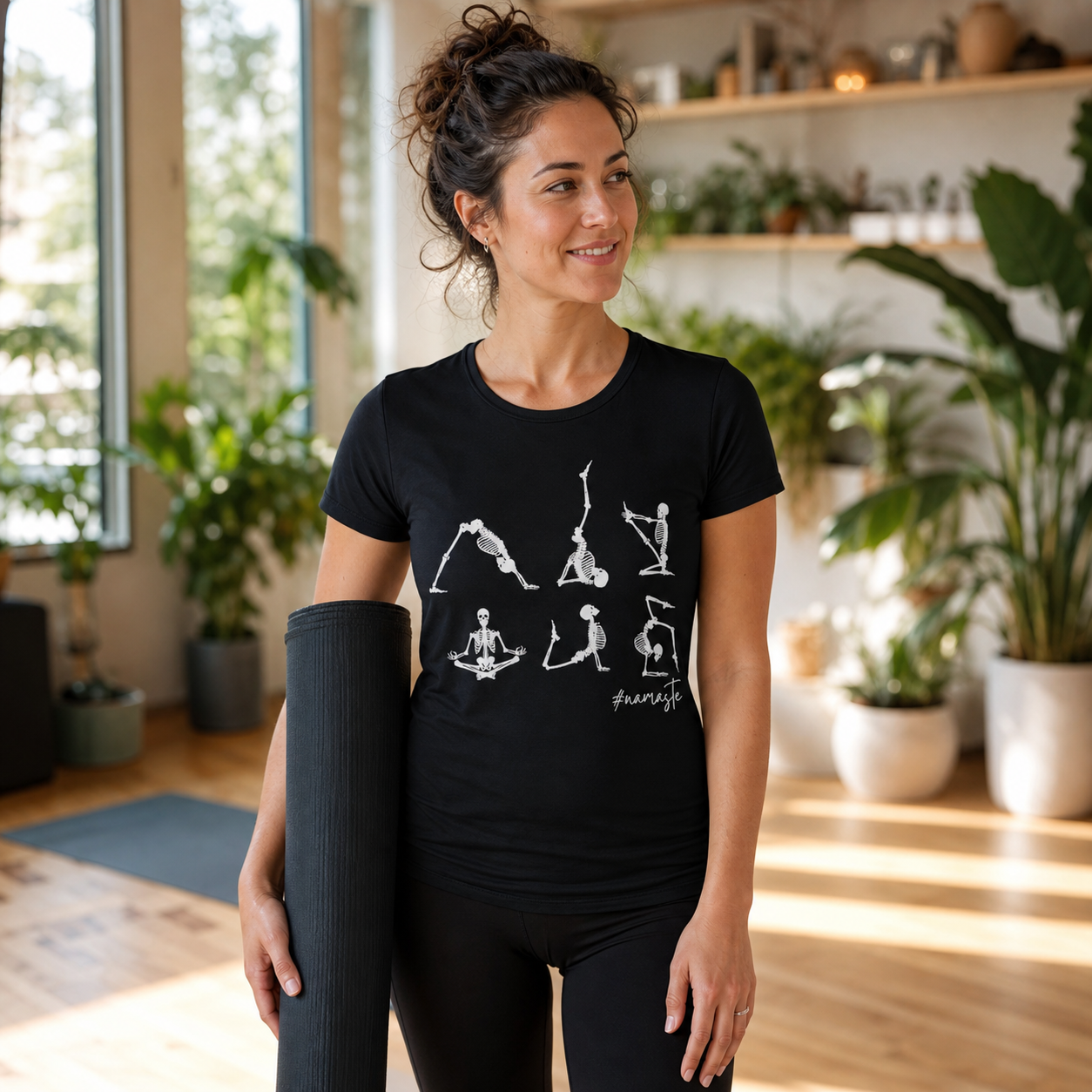 Woman wearing a black Namaste Skeleton yoga T-shirt in a sunlit yoga studio