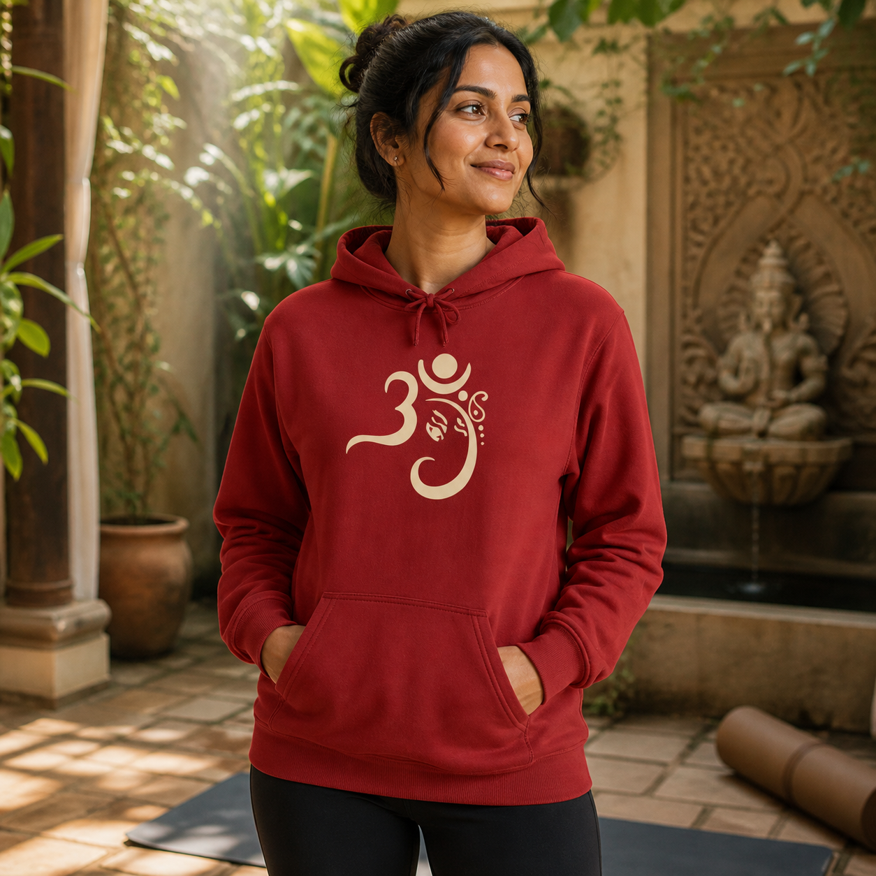 South Asian woman wearing red Om symbol yoga hoodie in a serene courtyard
