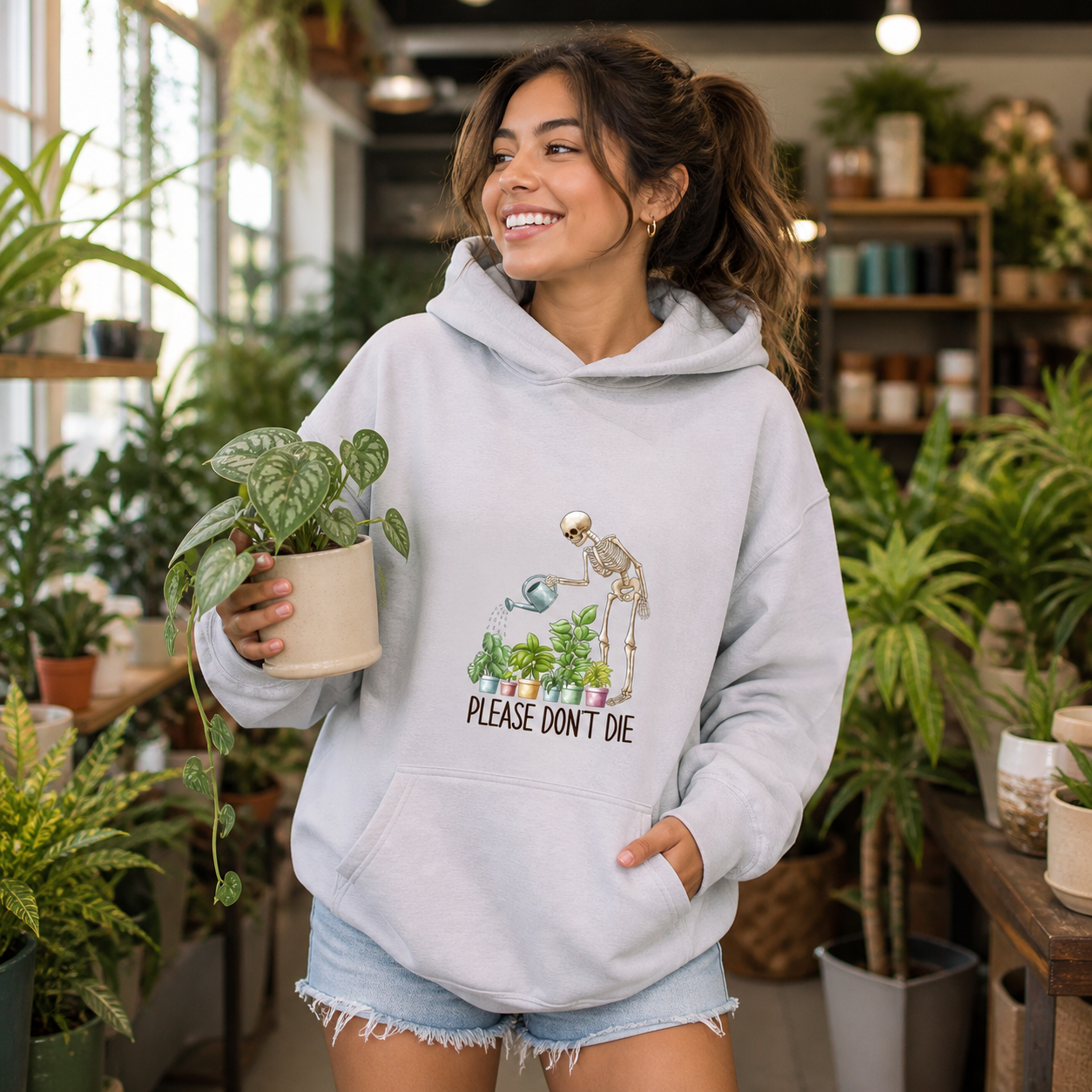 Young plant lover wearing Please Don't Die skeleton gardener hoodie in a plant shop