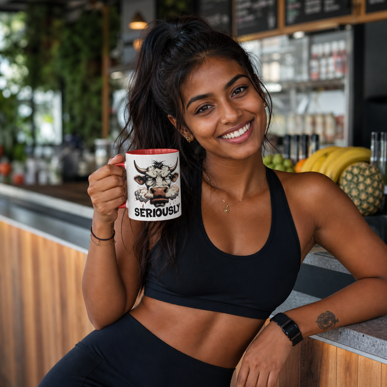 Athletic young woman holding red-accent Raging Bull Seriously mug at a smoothie bar