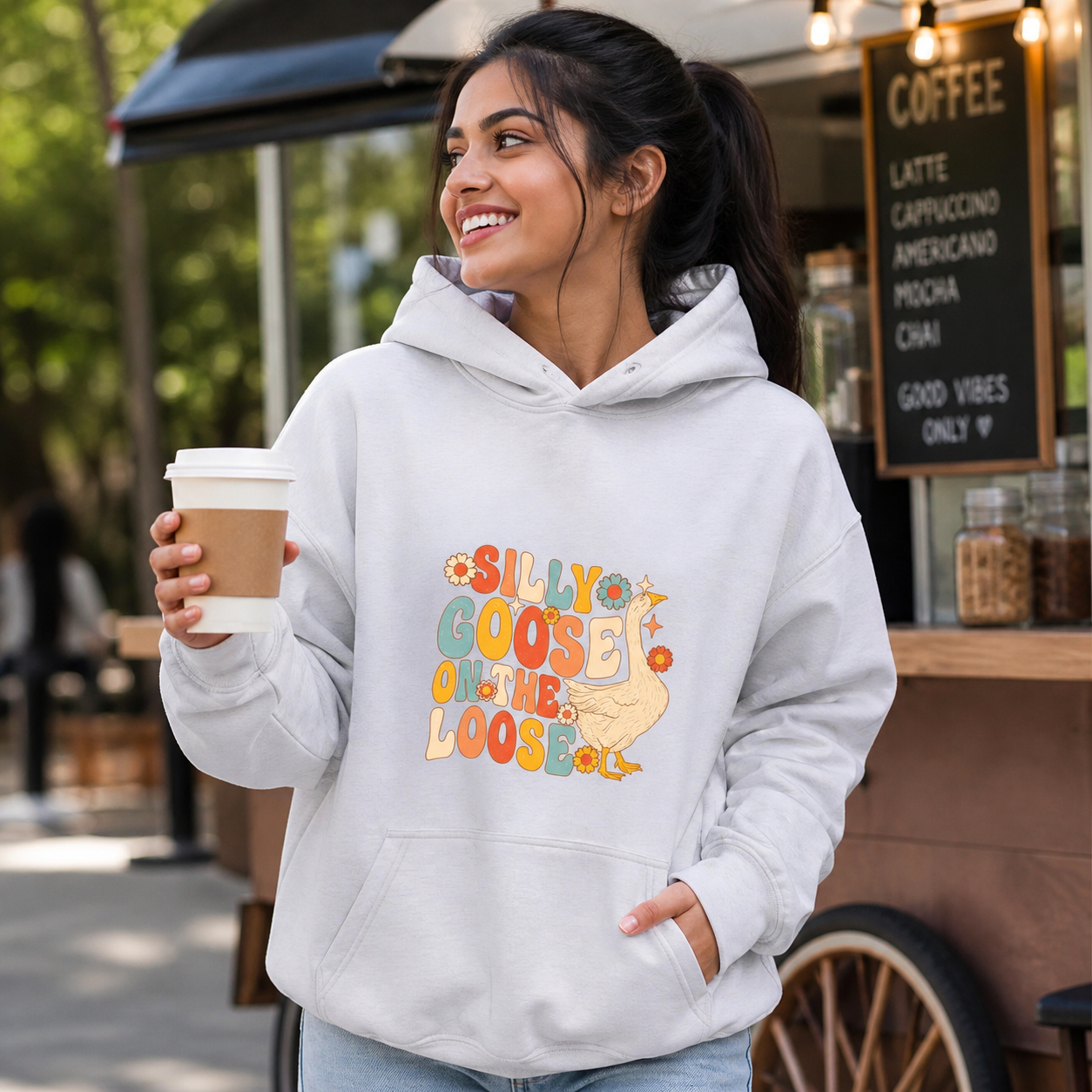 Young woman wearing Silly Goose on the Loose retro hoodie at a coffee cart