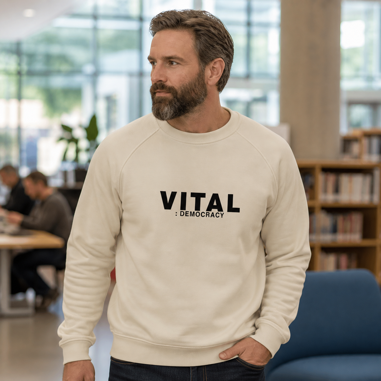 Man wearing cream Vital Democracy crewneck sweatshirt in a community space